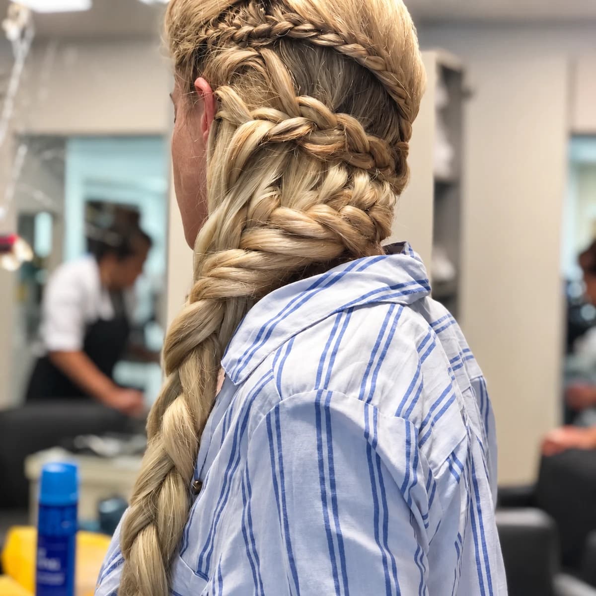 Trenza recogida con volumen y cola larga sobre una camisa a rayas.